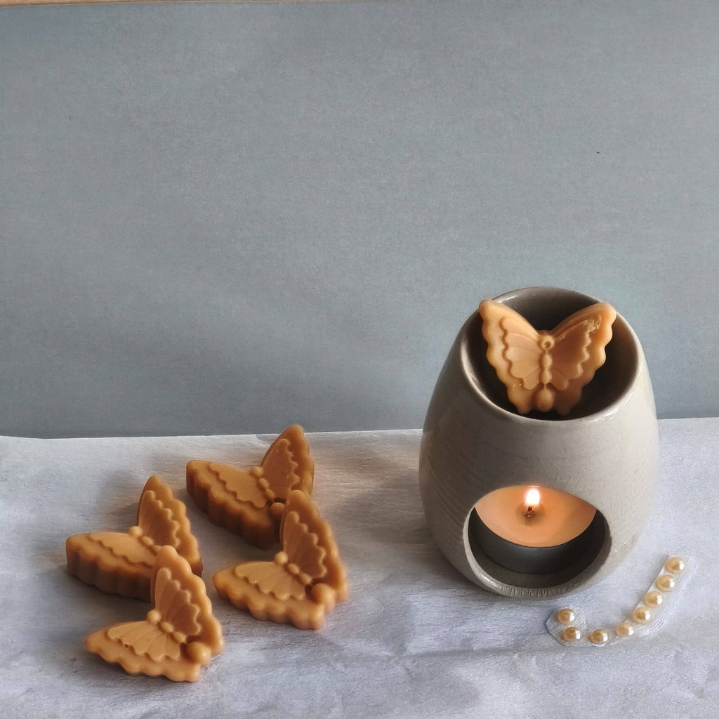Wax melts con forma de mariposa derritiéndose en quemador aromático
