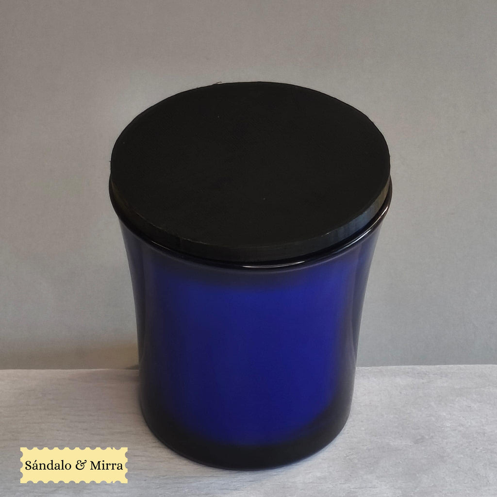 Vela espiritual de sándalo y mirra presentada en vaso de cristal azul con tapa.